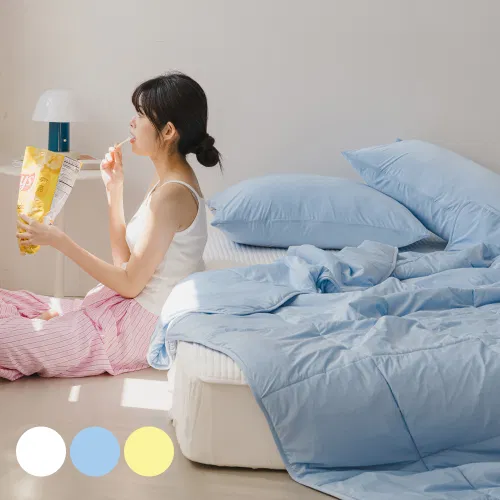 침대 위에 놓인 파스텔톤 침구 구성이 보입니다.